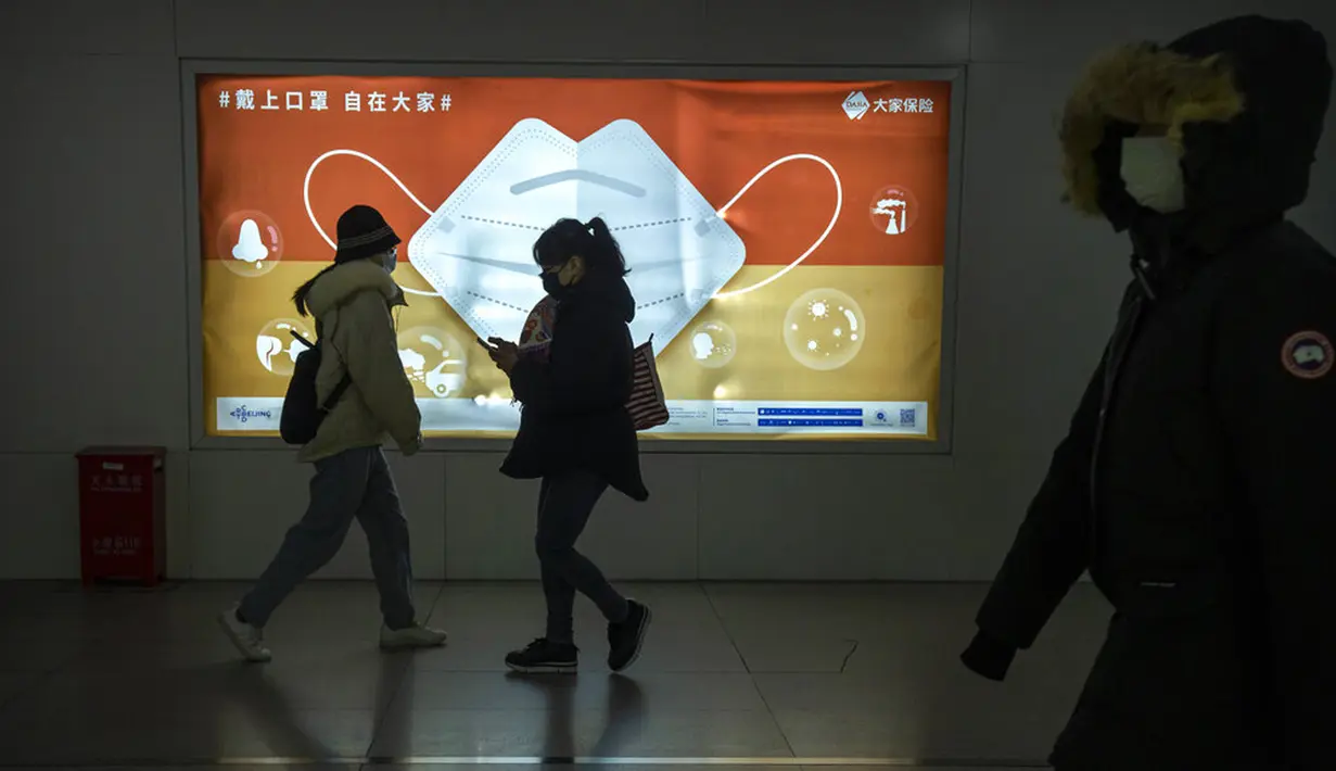 Para komuter yang mengenakan masker untuk melindungi diri dari COVID-19 berjalan melewati papan iklan yang mendorong warga untuk memakai masker di Beijing, China, Rabu (15/12/2021). China mendeteksi kasus kedua varian omicron pada seorang pria berusia 67 tahun. (AP Photo/Mark Schiefelbein)