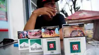 Seorang perokok tampak menunjukan bungkus rokok yang telah berganti peringatan bergambar di minimarket, Jakarta, Selasa (24/6/14). (Liputan6.com/Faizal Fanani)