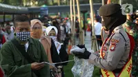 Personel polisi membagikan masker kepada calon penumpang kereta di area pedestrian Stasiun Terpadu Tanah Abang, Jakarta, Kamis (27/8/2020). Guna menekan penyebaran Covid-19, Polda Metro Jaya dan Kodam Jaya terus mengampanyekan pentingnya menaati protokol kesehatan. (Liputan6.com/Helmi Fithriansyah)