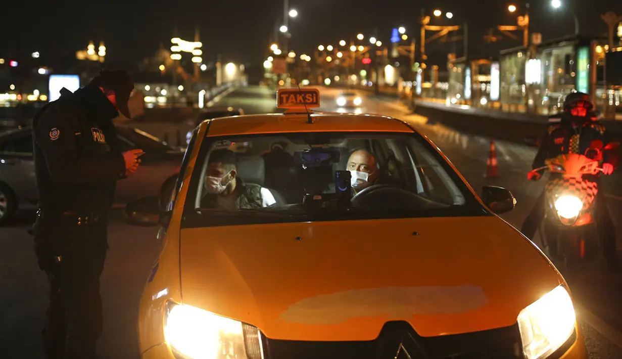 Polisi memeriksa penumpang kendaraan dan izin mereka di Jembatan Galata di atas Tanduk Emas, Istanbul, Turki, Kamis (29/4/2021). Presiden Turki Recep Tayyip Erdogan memberlakukan "penguncian penuh" hingga 17 Mei di tengah melonjaknya infeksi dan kematian akibat COVID-19. (AP Photo/Emrah Gurel)