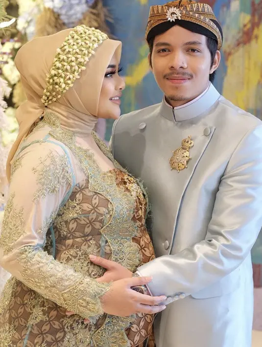 Kain lilit dan kebaya brukat tersebut dipadukan kerudung segi empat nude bergaya simple, yang dihiasi dengan bunga melati. @dhirmanputra