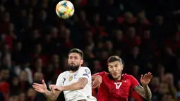 Striker Timnas Prancis, Olivier Giroud melompat saat berebut bola dengan pemain Albania, Kastriot Dermaku pada kualifikasi Grup H Piala Eropa 2020 di Arena Kombetare, Minggu (17/11/2019). Timnas Prancis sukses meraih kemenangan 2-0 atas timnas Albania. (AP/Hektor Pustina)