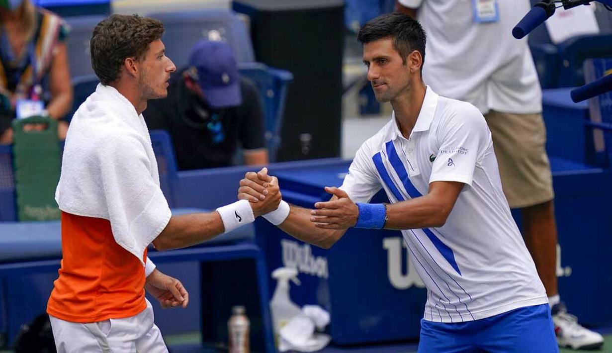 Petenis Serbia, Novak Djokovic, berjabat tangan dengan petenis Spanyol, Pablo Carreno Busta, pada AS Terbuka, di Flushing Meadows, Senin (7/9/2020). Djokovic didiskualifikasi karena memukulkan bola tenis ke arah hakim garis. (AP/Seth Wenig)