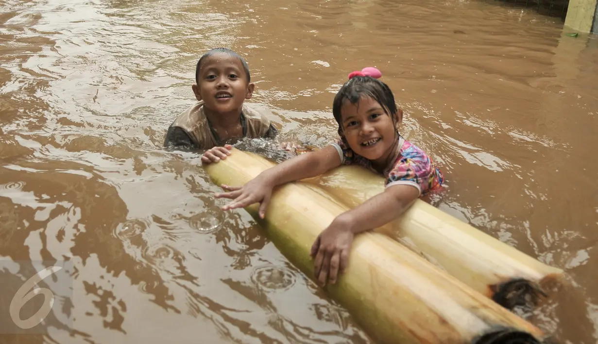 Dua anak bermain di tengah banjir di kawasan Cipinang Melayu, Jakarta Timur, Senin (20/2). Sebanyak 285 warga diungsikan akibat banjir setinggi 1 meter. (Liputan6.com/Yoppy Renato)