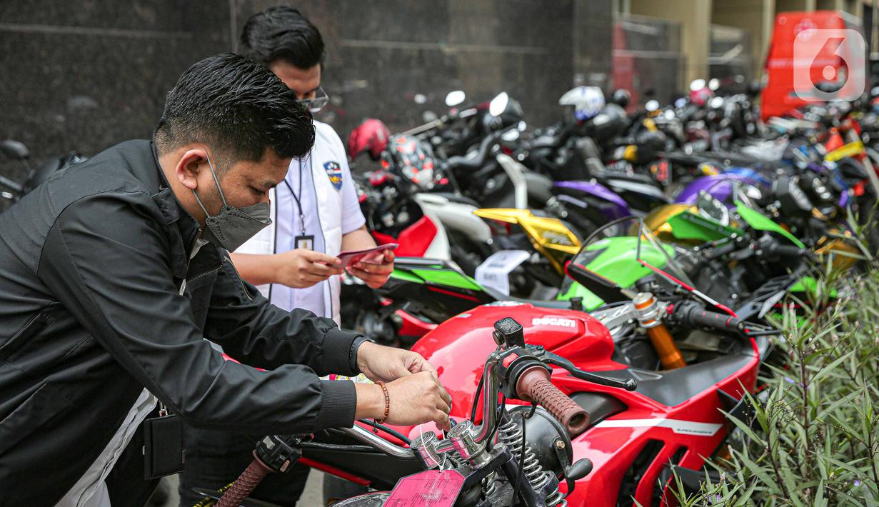 Polisi memberi label barang sitaan pada motor gede milik tersangka Quotex, Doni Salmanan di halaman Bareskrim Polri, Jakarta, Senin (14/3/2022). Selain sejumlah mobil mewah dan motor gede (moge), polisi juga menyita ponsel hingga akun YouTube Doni Salmanan. (Liputan6.com/Faizal Fanani)