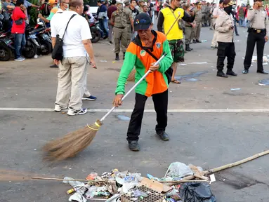 Petugas PPSU membersihkan sampah sisa perayaan Hari Buruh Internasional di kawasan Silang Barat Daya Monas, Jakarta, Rabu (1/5). Sampah yang berserakan di kawasan tersebut membuat Petugas PPSU bekerja ekstra keras untuk membersihkan kawasan tersebut. (Liputan6.com/Helmi Fithriansyah)