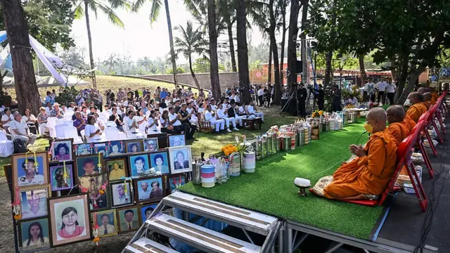 Para biksu duduk di panggung di samping potret korban tsunami saat orang-orang mengikuti upacara lintas agama di Taman Peringatan Tsunami Ban Nam Khem di Provinsi Phang Ng, Thailand selatan. [Lillian Suwanrumpha/AFP]