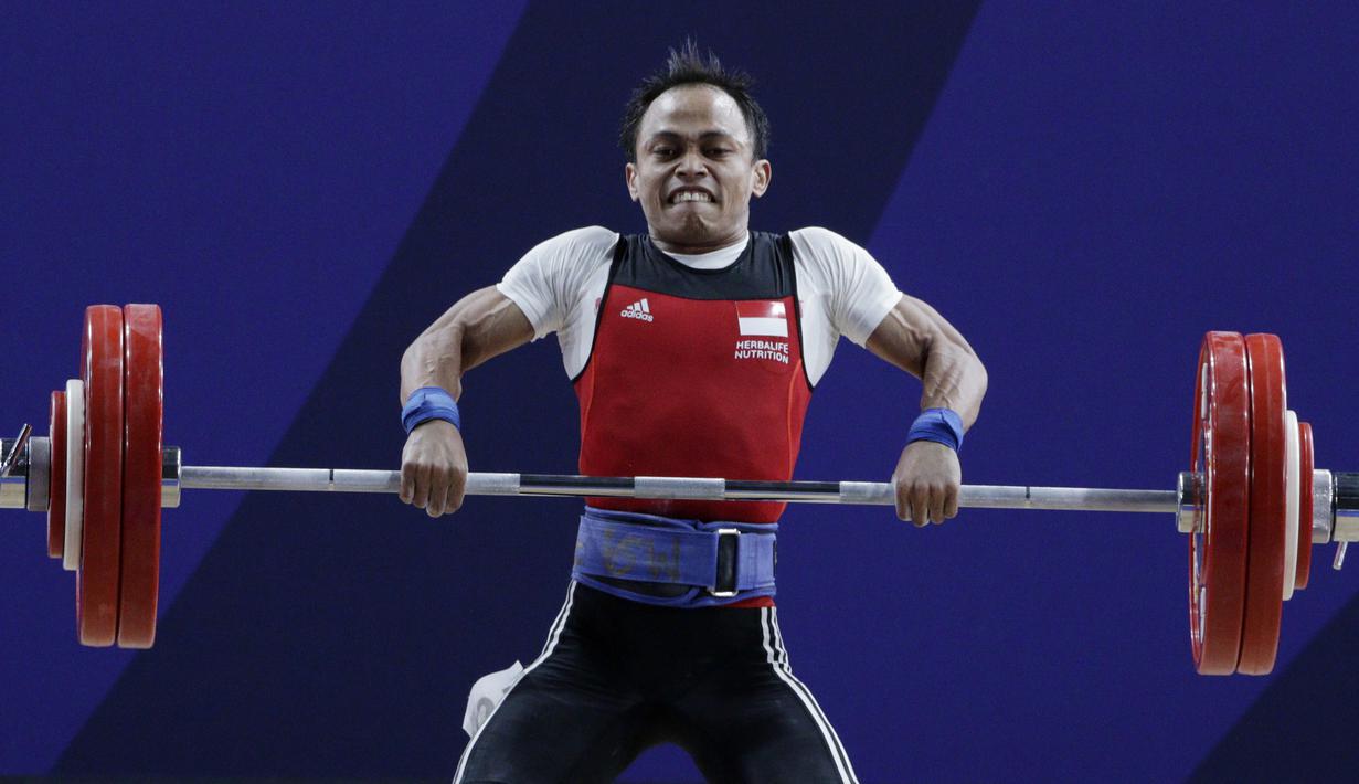 Lifter Suratman melakukan angkatan saat SEA Games 2019 cabang angkat besi nomor 55 kg di Stadion Rizal Memorial, Manila, Minggu (1/12). Dirinya meraih perak dengan total angkatan 250 kg. (Bola.com/M Iqbal Ichsan)