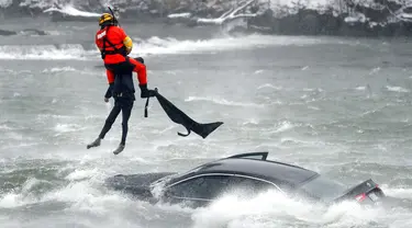 Penyelam Penjaga Pantai AS yang ditambatkan pada helikopter menarik tubuh pengendara mobil yang terjebak dalam arus deras di tepi Air Terjun Niagara, New York, AS, 8 Desember 2021. Wanita berusia 66 tahun meninggal setelah terjebak dua jam dalam air beku. (Sharon Cantillon/The Buffalo News via AP)