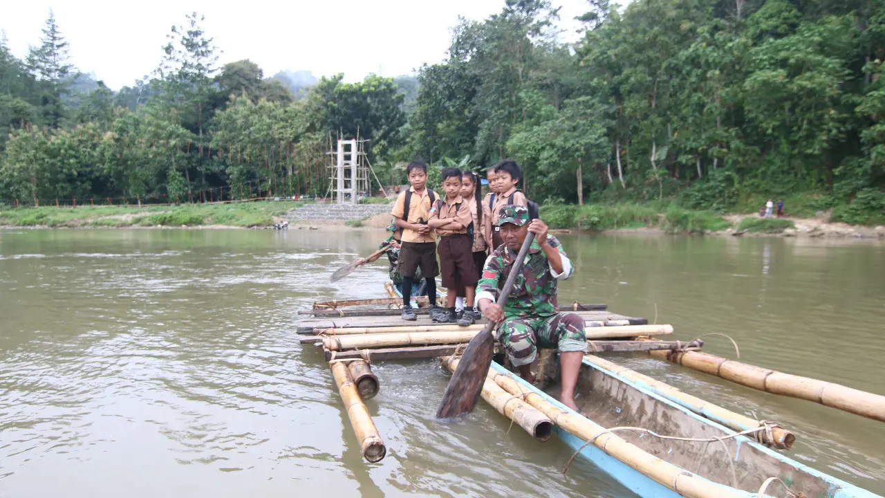Koptu Irwandi, salah satu Anggota Satgas TMMD ke 101 dari Kodim 1402/Polmas menyeberangkan anak sekolah menggunakan rakit bambu. (Ist)