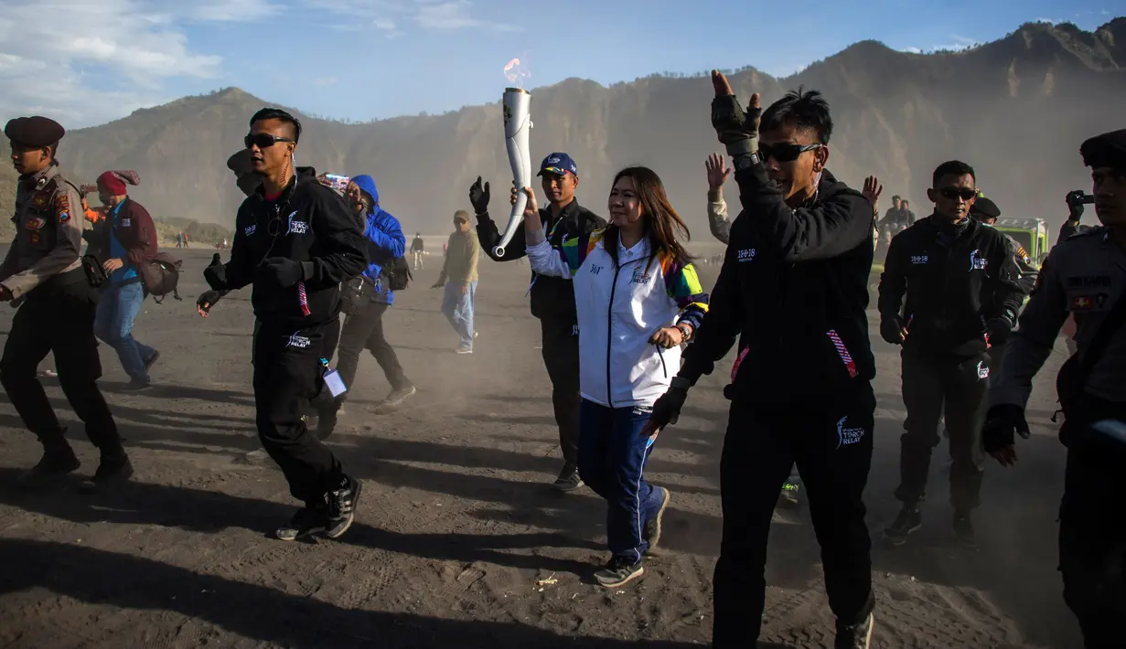 Legenda bulu tangkis Indonesia, Susi Susanti (tengah) membawa obor Asian Games 2018 di Gunung Bromo, Probolinggo, Jawa Timur, Sabtu (21/7). Sekitar 11 ribu atlet dari 45 negara Asia akan mengikuti Asian Games 2018. (JUNI KRISWANTO/AFP)