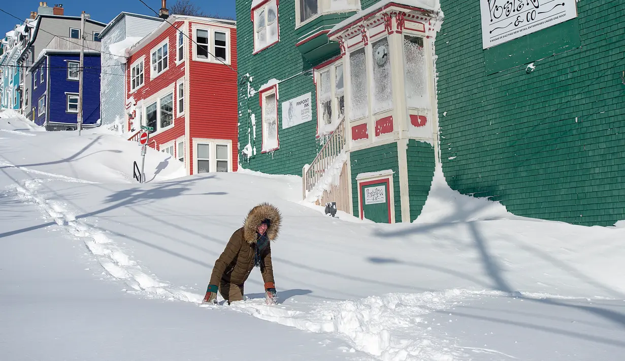 Warga berjalan melewati salju di Kota St John's, Newfoundland, Kanada, Sabtu (18/1/2020). St John's menghadapi keadaan darurat ketika salju tebal memaksa pusat-pusat bisnis tutup dan kendaraan dilarang melintas di jalan raya. (Andrew Vaughan/The Canadian Press via AP)