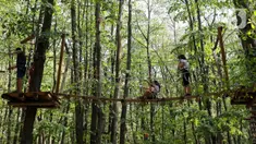 Pengunjung melintasi jalan setapak antarpepohonan di Edenland Park, Balotesti, Rumania, Rabu (4/10/2023). Edenland Park merupakan tempat petualangan terbesar di Rumania. (Liputan6.com/Herman Zakharia)