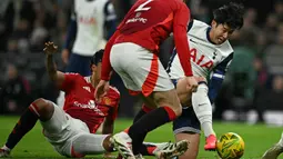 Pemain Tottenham Hotspur, Son Heung-min (kanan) berusaha melepaskan diri dari penjagaan pemain Manchester United pada laga perempat final Carabao Cup 2024/2025 di Tottenham Hotspur Stadium, London, Jumat (20/12/2024). (AFP/Ben Stansall)