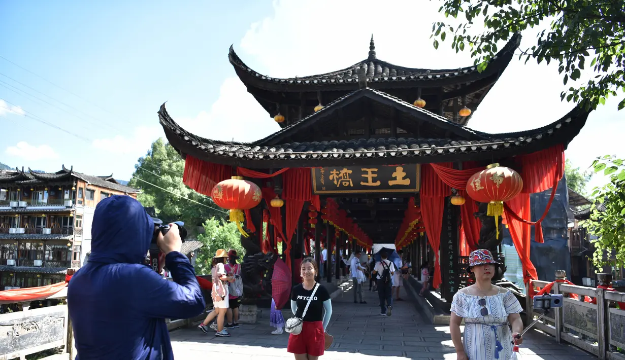 Para wisatawan mengabadikan foto di objek wisata Kota Furong di Wilayah Yongshun, Provinsi Hunan, China tengah (2/8/2020). Dengan menerapkan sejumlah langkah pencegahan epidemi, objek wisata tersebut mencatat peningkatan kunjungan turis selama liburan musim panas. (Xinhua/Chen Sihan)