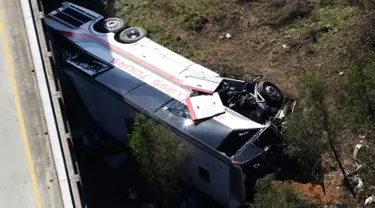 Sebuah bus carteran jatuh usai menabrak pembatas akibat kecelakaan di Loxley, Alabama (13/3). Bus tersebut membawa anggota band SMA di Texas pulang dari Disney World. (AP Photo / Dan Anderson)