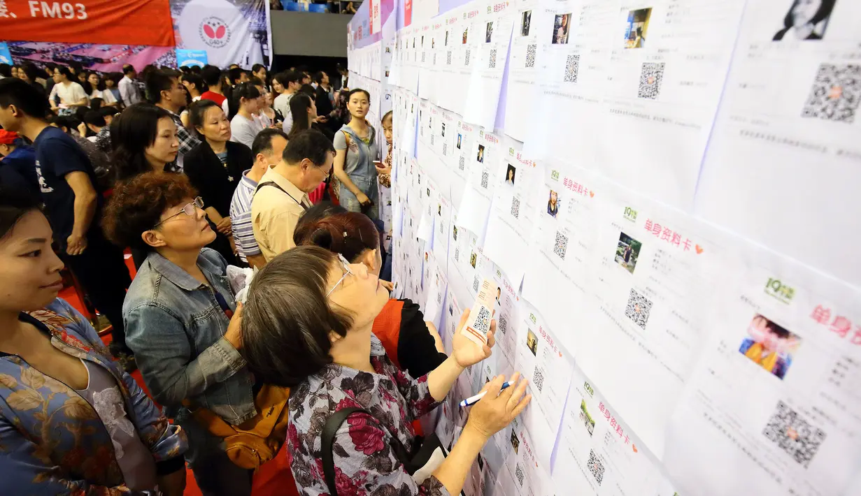 Orang-orang melihat papan informasi yang menampilkan data pria dan wanita lajang pada acara perjodohan di Hangzhou, China, Minggu (29/5/2016). Acara yang diselenggarakan di Universitas Zhejiang ini menarik minat lebih dari 20.000 orang lajang. (STR/AFP)