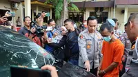 Pelaku tabrak lari saat dihadirkan oleh Kepala Polresta Pekanbaru dengan barang bukti mobil. (Liputan6.com/M Syukur)