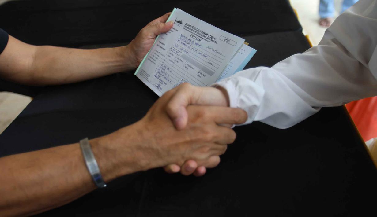 Untuk diketahui, besaran zakat fitrah yang harus dikeluarkan adalah berupa beras atau makanan pokok seberat 2,5 kg atau 3,5 liter per jiwa. Tampak dalam foto, petugas Unit Pengelola Zakat (UPZ) melayani pembayaran zakat, fidyah, kafarat, infaq, dan shadaqah di teras Masjid Istiqlal, Jakarta, Minggu 15 Maret 2026. (Kapanlagi.com/Budy Santoso)