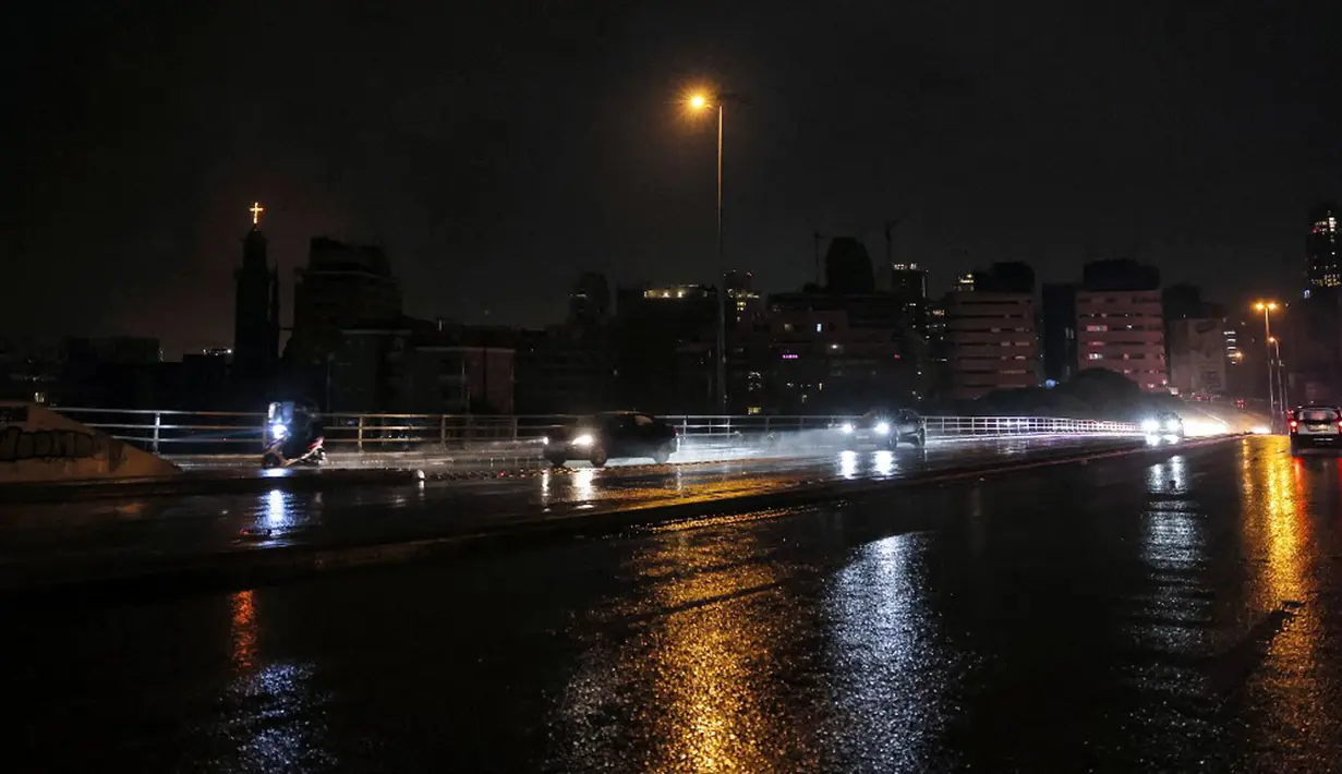 Kendaraan melaju melewati banyak bangunan dalam kegelapan total di Jembatan Cincin, Beirut, Lebanon, 14 Desember 2021. Semarak jelang Natal yang biasa terjadi di Beirut, tak lagi terasa tahun ini karena krisis keuangan terburuk di Lebanon. (JOSEPH EID/AFP)