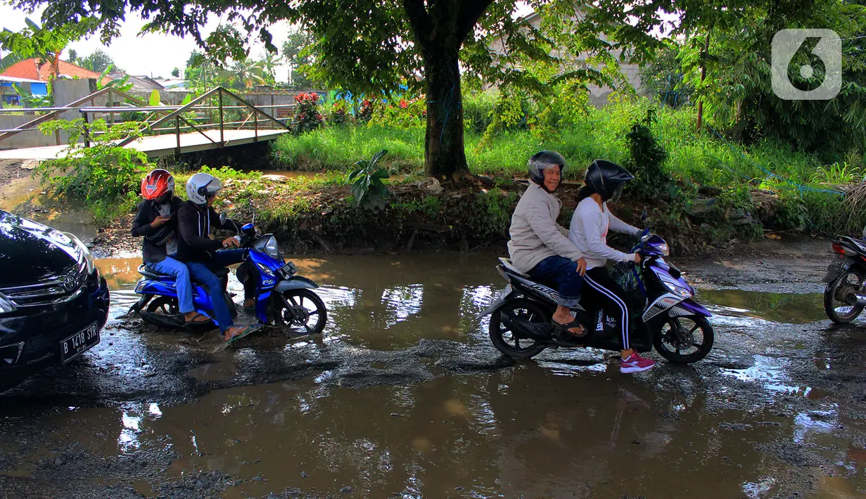 Pengendara motor menerobos lubang yang ada di Jalan Raya Bojonggede, Bogor, Jawa Barat, Sabtu (22/2/2020). Jalan Raya Bojonggede yang berlubang hingga kini belum juga diperbaiki pemerintah setempat membuat kondisi lalu lintas tersendat (merdeka.com/Magang/Muhammad Fayyadh)