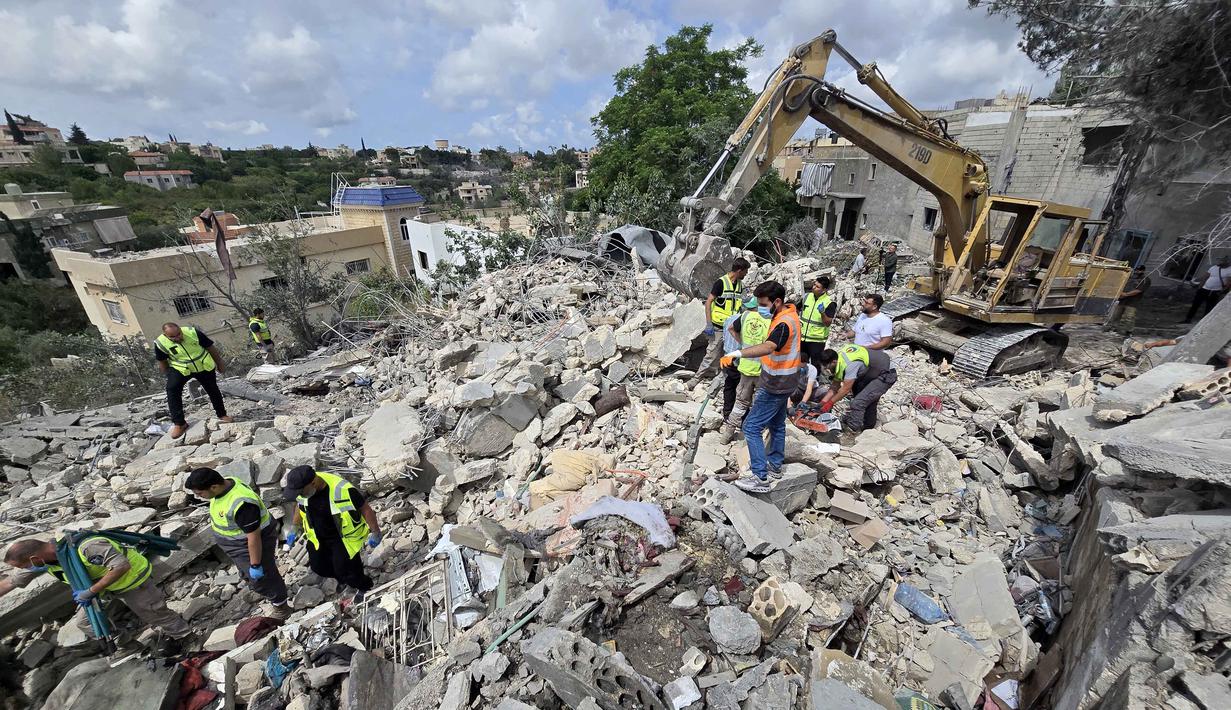 Para pekerja pertahanan sipil Lebanon menyisir reruntuhan, sehari setelah serangan Israel di desa Deir Qanun al-Nahr, Lebanon Selatan, pada Rabu 20 Mei 2026. (KAWNAT HAJU/AFP)