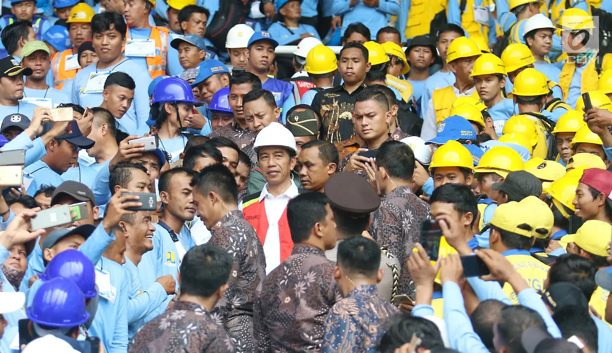 Para pekerja konstruksi berebut foto dengan Presiden Joko Widodo (Jokowi) di Stadion GBK, Jakarta, Kamis (19/10). Jokowi akan menyaksikan sertifikasi 9.700 tenaga kerja konstruksi di seluruh Indonesia secara serentak. (Liputan6.com/Angga Yuniar)