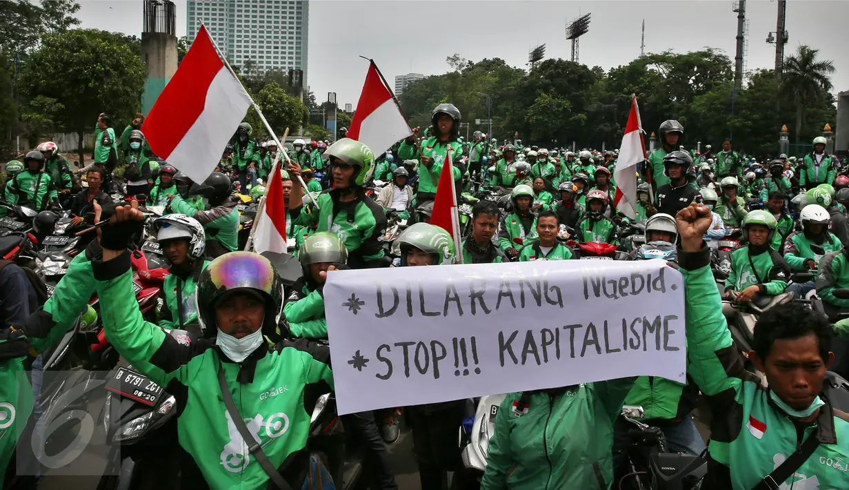 Massa driver Gojek membawa spanduk dan bendera merah putih saat berkumpul di jalan Asia Afrika, Jakarta,  Senin (3/10). Mereka akan berkonvoi menuju kantor Gojek di kawasan Kemang, Jakarta Selatan, untuk menyampaikan aspirasi. (Liputan6.com/Johan Tallo)