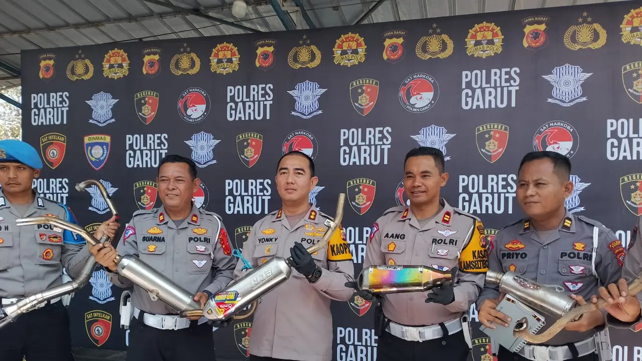 Kapolres Garut AKBP Rohman Yonky Dilatha, didampingi Kasat Lantas Iptu Aang Andi Suhandi menunjukan ragam knalpot brong yang disita petugas dalam rilis kasus di Mapolres Garut, Selasa (31/10/2023). (Liputan6.com/Jayadi Supriyadin)