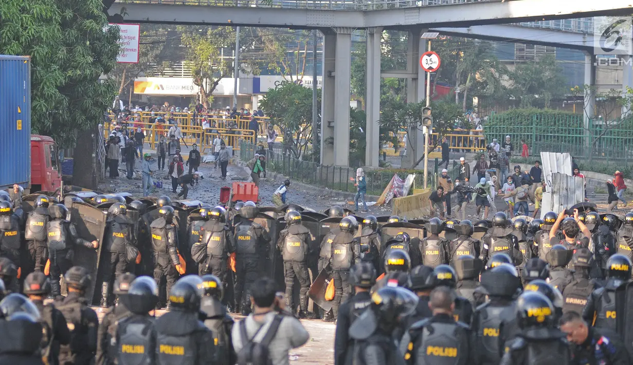 Polisi membuat barikade saat terjadi bentrok dengan massa aksi di kawasan Tanah Abang, Jakarta, Rabu (22/5/2019). Beberapa kelompok massa menggunakan benda-benda keras hingga mercon untuk menahan laju petugas keamanan. (Liputan6.com/Herman Zakharia)