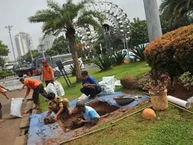 Pekerja mengangkut tanah saat pembuatan sumur resapan di Monas, Jakarta, Jumat (22/7). Pembuatan puluhan sumur resapan itu guna mengantisipasi genangan air hujan dan menyimpan air di Kawasan Monas dan depan Istana Merdeka. (Liputan6.com/Gempur M Surya)