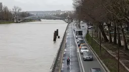 Sejumlah kendaraan melintas di samping sungai Seine yang meluap, Paris, Prancis (5/1). Meluapnya air di sungai Seine akibat tidak mampu menampung debit air setelah hujan terjadi terus-menerus. (AFP Photo/Ludovic Marin)