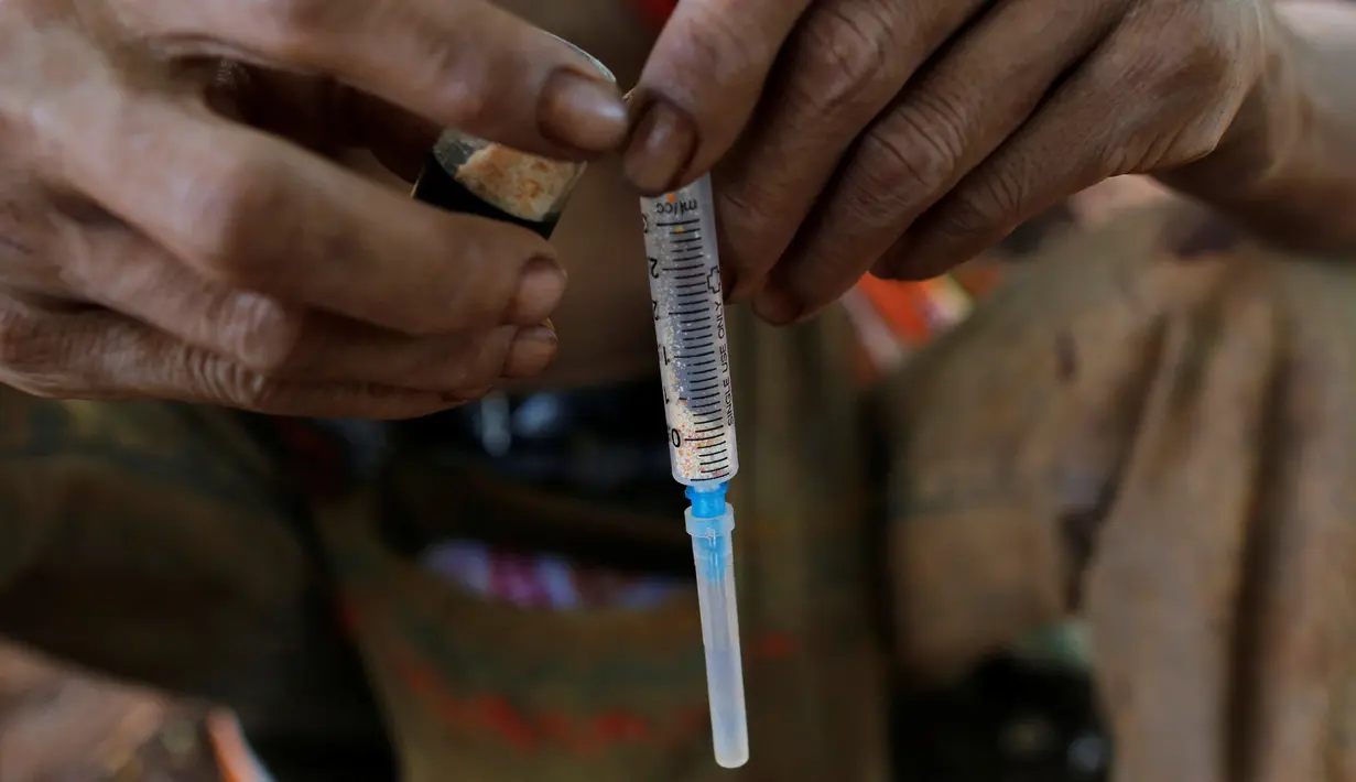 Seorang pria menyiapkan jarum suntik sebelum menyuntikan heroin ketubuhnya di jalanan Man Sam, Myanmar, 11 Juli 2016. Tanpa memikirkan sekelilingnya pengguna narkoba ini mengkonsumsi obat-obatan terlarang dimuka umum. (REUTERS/Soe Zeya Tun)