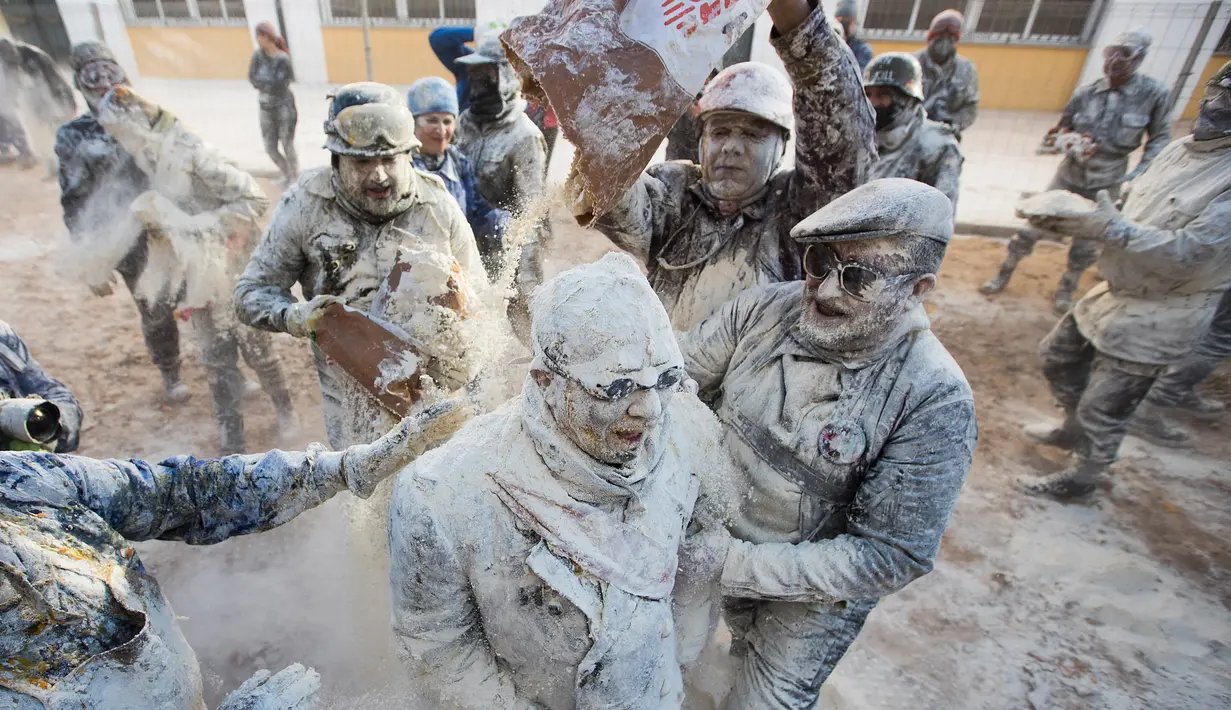 Orang-orang yang mengenakan pakaian militer tiruan ikut serta dalam perang makanan "Els Enfarinats" di Kota Ibi, Spanyol, 28 Desember 2022. (JAIME REINA/AFP)