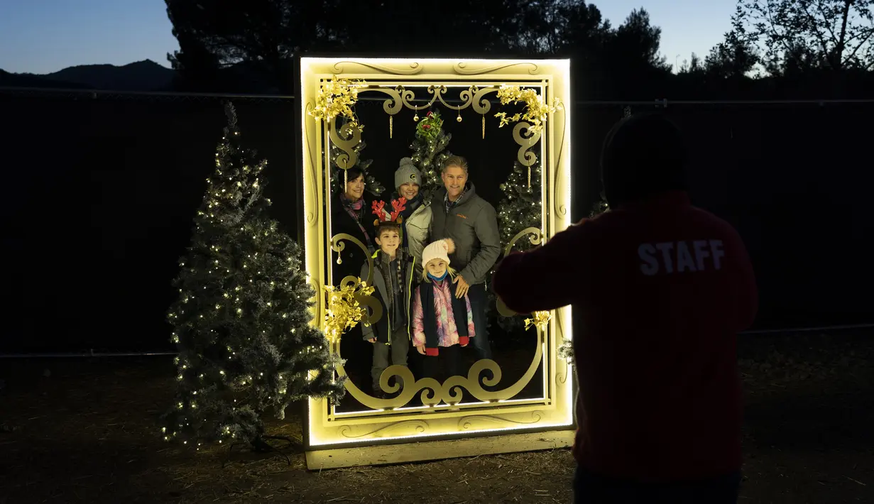 Satu keluarga berpose untuk foto pada pertunjukan cahaya Holiday Road di Calabasas, California, Amerika Serikat, 10 Desember 2021. Holiday Road digelar sepenuhnya setelah pandemi COVID-19 mengubah festival cahaya tahunan ini menjadi acara drive-thru tahun lalu. (AP Photo/Jae C.Hong)