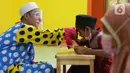 Seorang anak mencium tangan Yahya Edward usai mengaji di Pinang, Kota Tangerang, Banten, Kamis (29/4/2021). Mengajar ngaji menggunakan kostum badut tersebut untuk memotivasi anak-anak agar tetap semangat belajar sekaligus untuk menghibur anak didiknya. (Liputan6.com/Angga Yuniar)