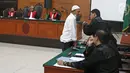 Terdakwa kasus penembakan dr Letty Sultri, dr Helmi berdiskusi dengan kuasa hukumnya saat sidang mendengarkan dakwaan di PN Jakarta Timur, Kamis (29/3). Helmi didakwa menembak istrinya sebanyak enam kali di bagian badan. (Liputan6.com/Herman Zakharia)