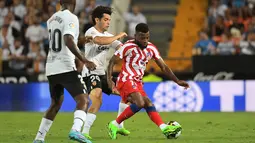 Penyerang Valencia, Fran Perez (tengah) berusaha merebut bola dari gelandang Atletico Madrid, Thomas Lemar (kanan) dalam pertandingan lanjutan La Liga Spanyol di stadion Mestalla di Valencia (30/8/2022). Atletico Madrid menang tipis atas tuan rumah Valencia 1-0. (AFP/Jose Jordan)