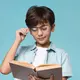 Seorang anak laki-laki sedang memegang kacamata sambil membaca buku (Foto Dok: Freepik/freepik).