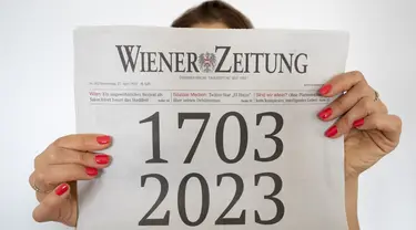 Seorang wanita memegang koran "Wiener Zeitung" terbitan 27 April 2023 dengan halaman depan yang menggambarkan usia surat kabar tersebut selama 320 tahun di Wina, Austria, 27 April 2023. Wiener Zeitung adalah salah satu surat kabar tertua di dunia. (JOE KLAMAR/AFP)