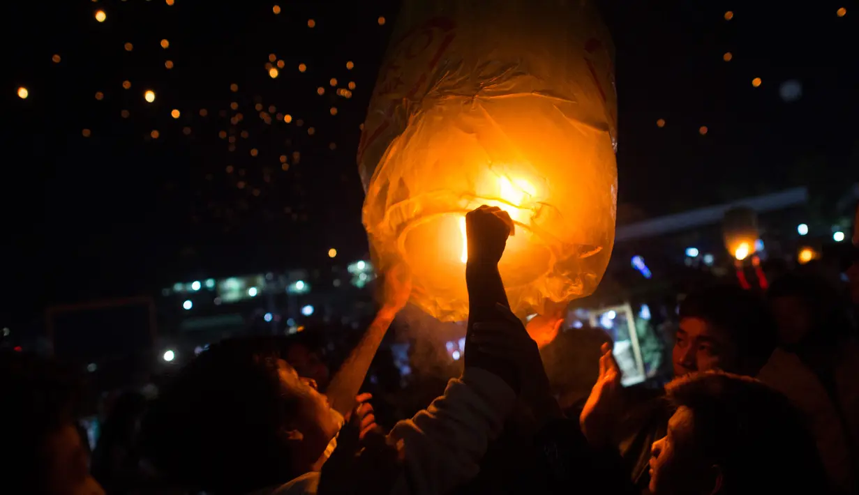 Para peserta melepaskan lentera ke udara selama Festival Tazaungdaing di Taunggyi, Myanmar pada 14 November 2018. Perayaan festival ini digelar saat bulan purnama bersinar di langit malam Myanmar. (Ye Aung THU / AFP)