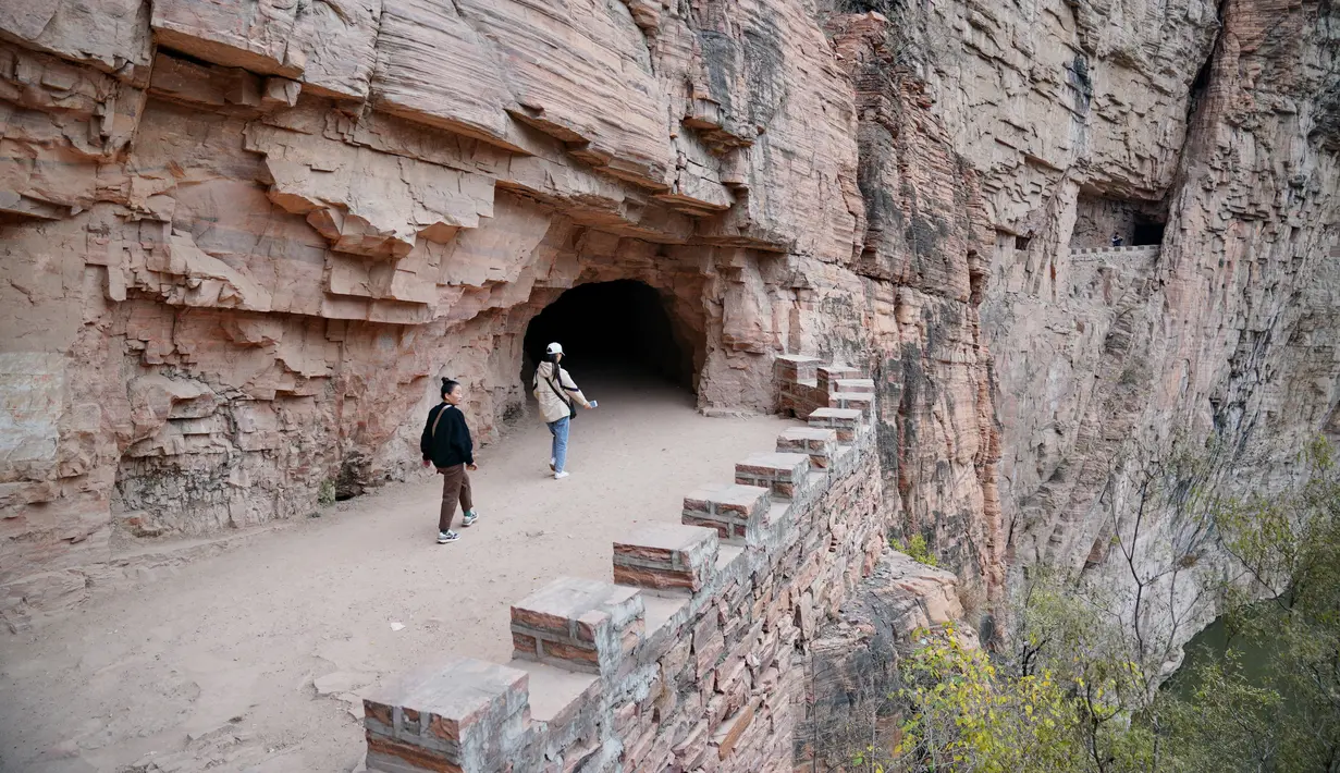 Wisatawan menyusuri jalur di tebing dekat Waduk Xiagou yang berada di Chaiguan, Kota Shahe, Provinsi Hebei, China utara, pada 28 Oktober 2020. Jalur tebing pada dinding Waduk Xiagou ini digali secara manual pada 1970-an. (Xinhua/Mu Yu)