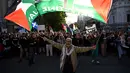 Para pengunjuk rasa mengibarkan bendera dan membawa plakat saat mereka berunjuk rasa selama kunjungan Presiden Israel, Isaac Herzog, di Melbourne, Australia, pada Kamis 12 Februari 2026. Ribuan orang menggelar aksi unjuk rasa di Melbourne, Australia. (WILLIAM WEST/AFP)