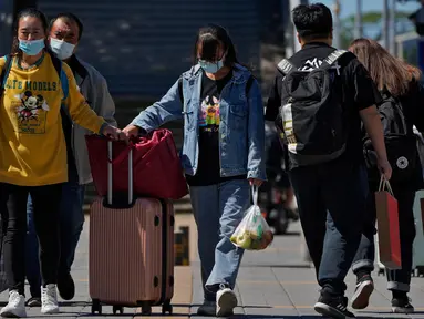 Wisatawan mengenakan masker wajah dengan barang bawaan mereka meninggalkan stasiun kereta api Beijing di Beijing, Selasa (6/9/2022). China lockdown jutaan warganya di bawah pembatasan ketat COVID-19. (AP Photo/Andy Wong)