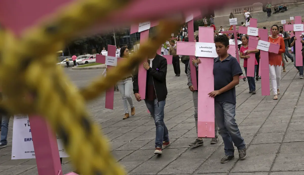 Sejumlah orang membawa salib berwarna pink saat memperingati Hari Internasional untuk Penghapusan Kekerasan terhadap Perempuan di Meksiko, Rabu (25/11). Setiap tahunnya, kegiatan ini berlangsung dari tanggal 25 November. (REUTERS/Daniel Becerril)