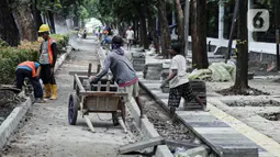 Pekerja menyelesaikan proyek revitalisasi pedestrian di kawasan Jalan Pattimura, Jakarta, Rabu (8/6/2022). Dinas Bina Marga DKI Jakarta merevitalisasi pedestrian dengan memperlebar menjadi tiga meter sehingga cukup luas untuk memberikan kenyamanan para pejalan kaki. (Liputan6.com/Faizal Fanani)