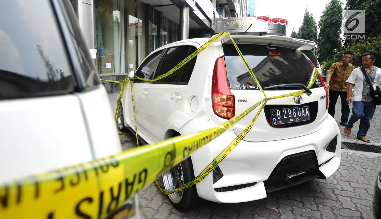 Warga melintas di belakang mobil milik tersangka kasus penipuan calon jamaah umroh yang disita Bareskrim Mabes Polri, Jakarta, Selasa (22/8). Hingga kini, polisi telah menetapkan tiga tersangka kasus tersebut. (Liputan6.com/Helmi Fithriansyah)