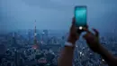Gambar pada 19 Agustus 2019 memperlihatkan seorang turis mengambil gambar panorama skyline (kaki langit) kota Tokyo dari dek observasi Menara Roppongi Hills. Wisatawan dapat melihat berbagai gedung pencakar langit yang semua tertata rapi di kota terkenal sibuk ini. (AP Photo/Jae C. Hong)