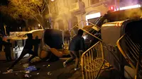 Demonstran pro kemerdekaan Catalonia merusak tempat sampah dan besi pembatas di Barcelona, Spanyol, Minggu (25/3). Demonstran memprotes penangkapan mantan pemimpin ekstrem Catalonia, Carles Puigdemont. (Foto AP/Emilio Morenatti)