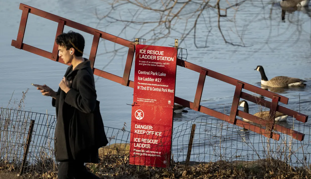 Pejalan kaki melewati stasiun tangga penyelamat es di pusat Central Park, wilayah Manhattan, New York, Senin (30/1/2023). New York City juga akan memecahkan rekor kedua, untuk periode waktu terlama tanpa salju. Pada Senin, sudah 327 hari tanpa akumulasi salju. Rekornya adalah 332 hari — rekor beruntun yang dipecahkan pada Desember 2020. (AP Photo/John Minchillo)